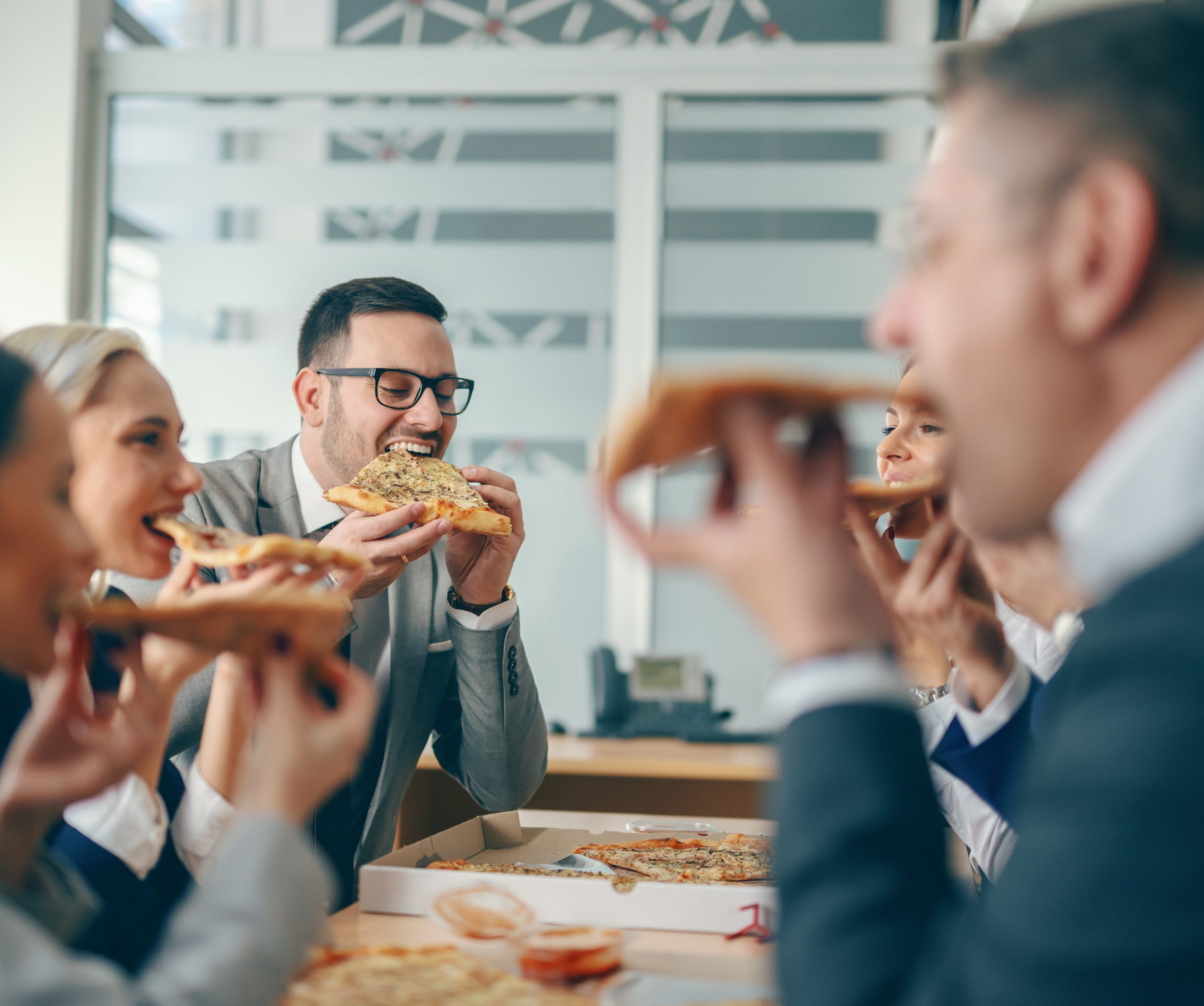 Business people sitting at boardroom and having pizza for lunch.