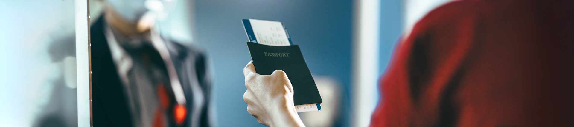 Cropped shot of a female passenger giving her passport with flight ticket to airline attendant behind check-in counter during covid-19 outbreak. Woman traveler doing check-in at the airport.